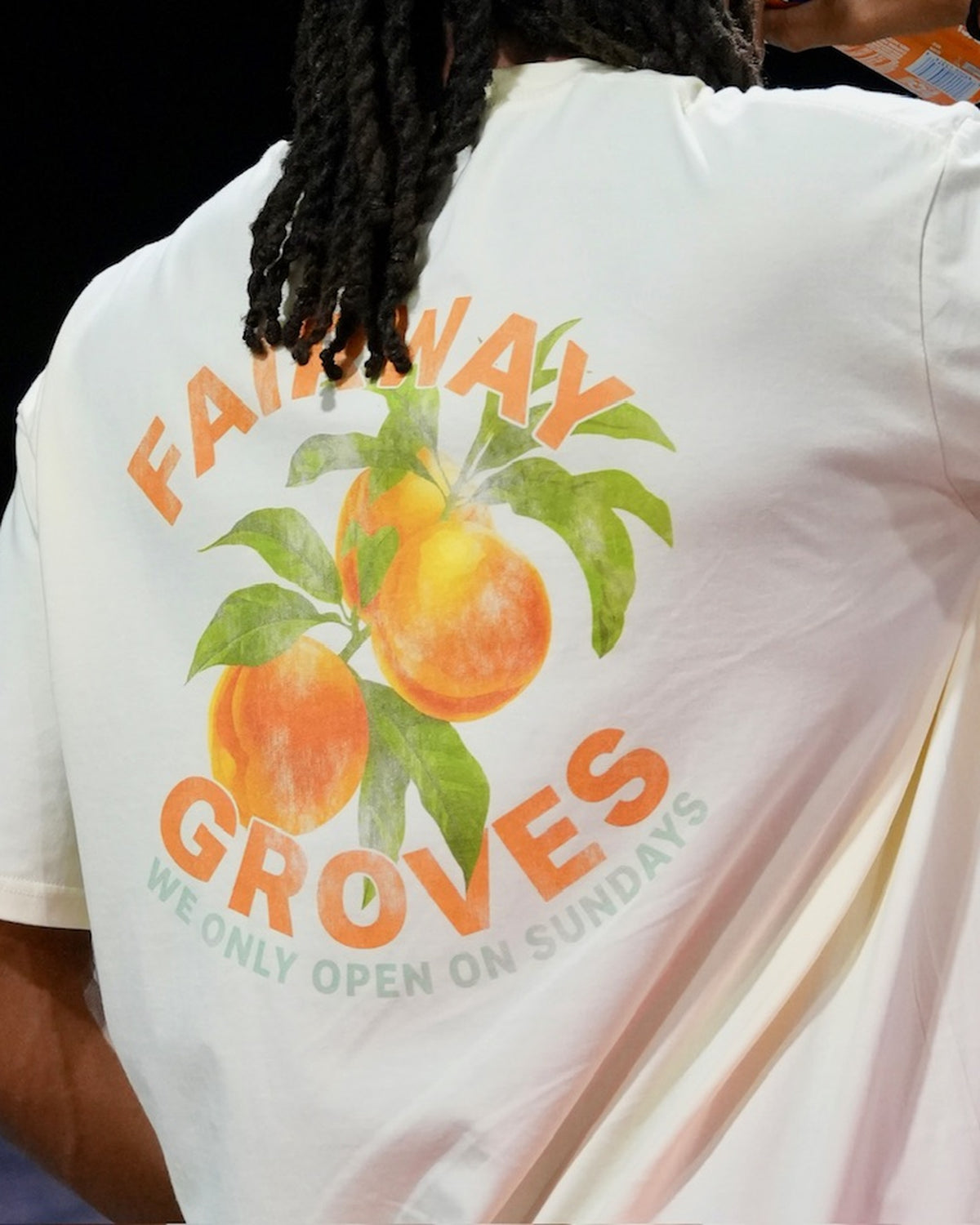 Golfer wearing the Fairway Groves Tee at night, back graphic visible under dramatic lighting.
