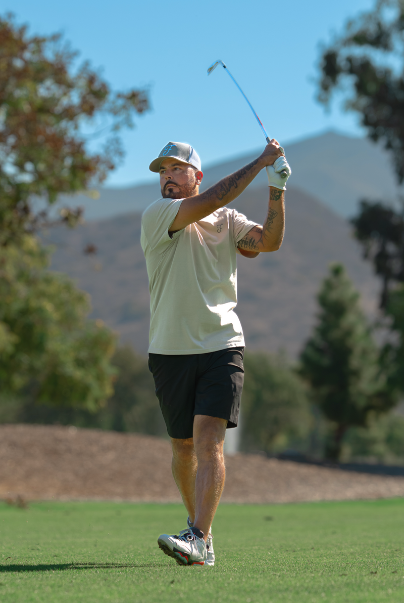 Man playing golf on a course with trees and mountains in the background
