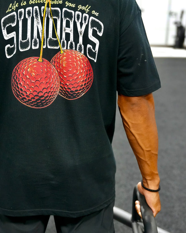 Close-up of the Sunday Cherries Tee's back graphic — two cherries made of golf balls with "Life is better when you golf on Sundays."
