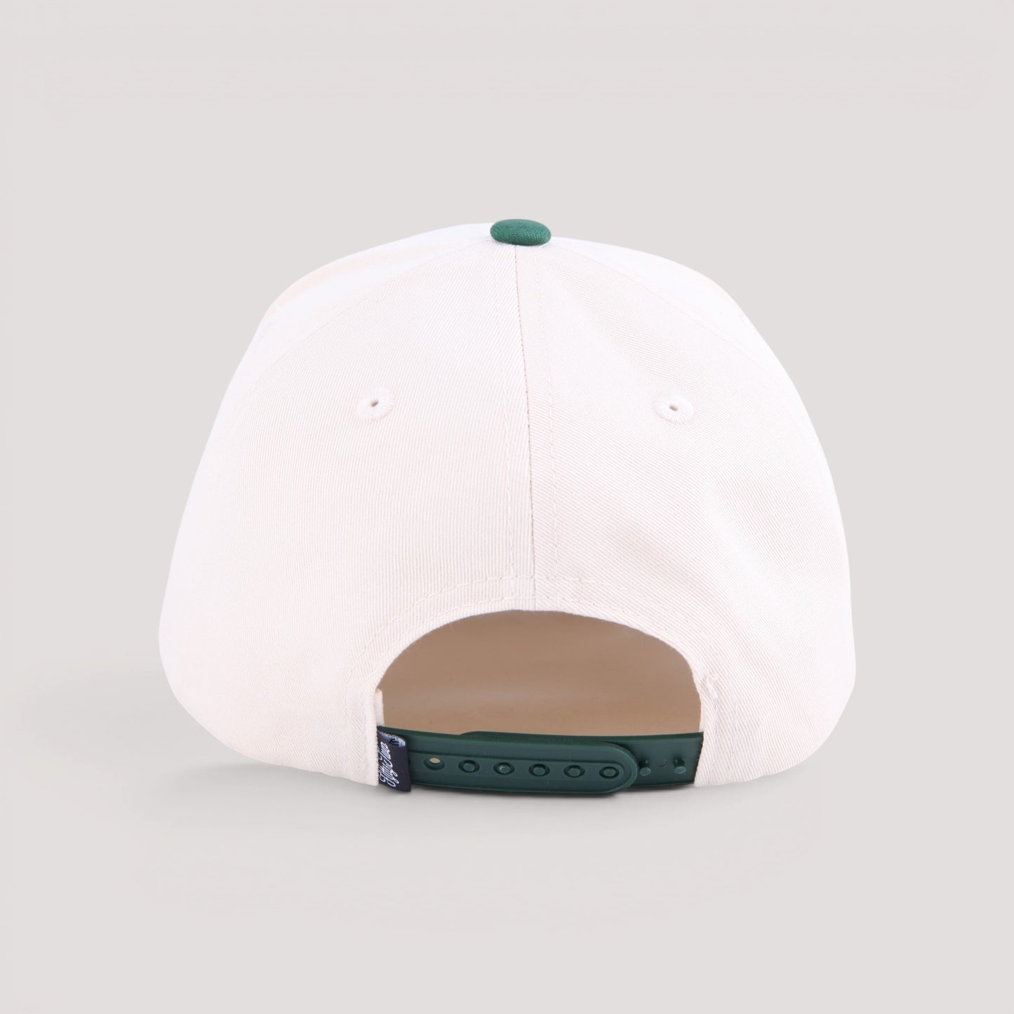 The back view of a tan baseball cap with a dark green button on top and a dark green adjustable strap at the bottom, shown on a light gray background.
