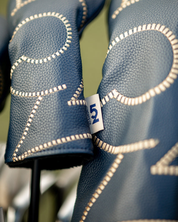 Close-up of the hand-stitched cream detailing and woven '52 Sundays Co.' tag on a 52 Sundays leather headcover