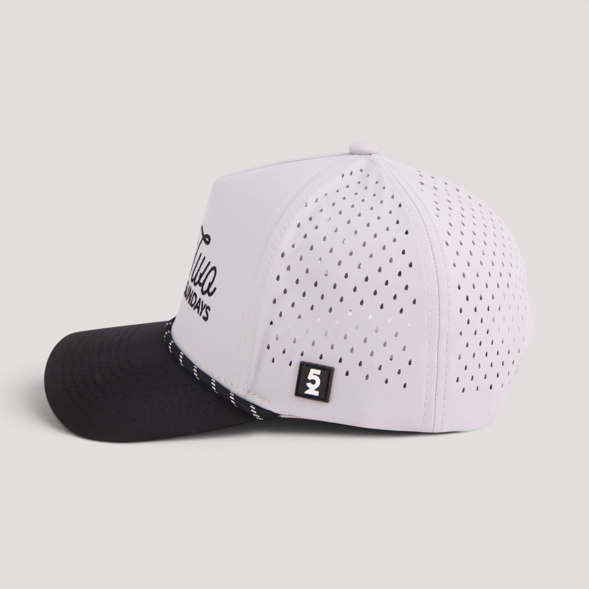 A grey and black golf hat with a perforated front panel, featuring a black visor, a small black square patch with a white '52' on the side.
