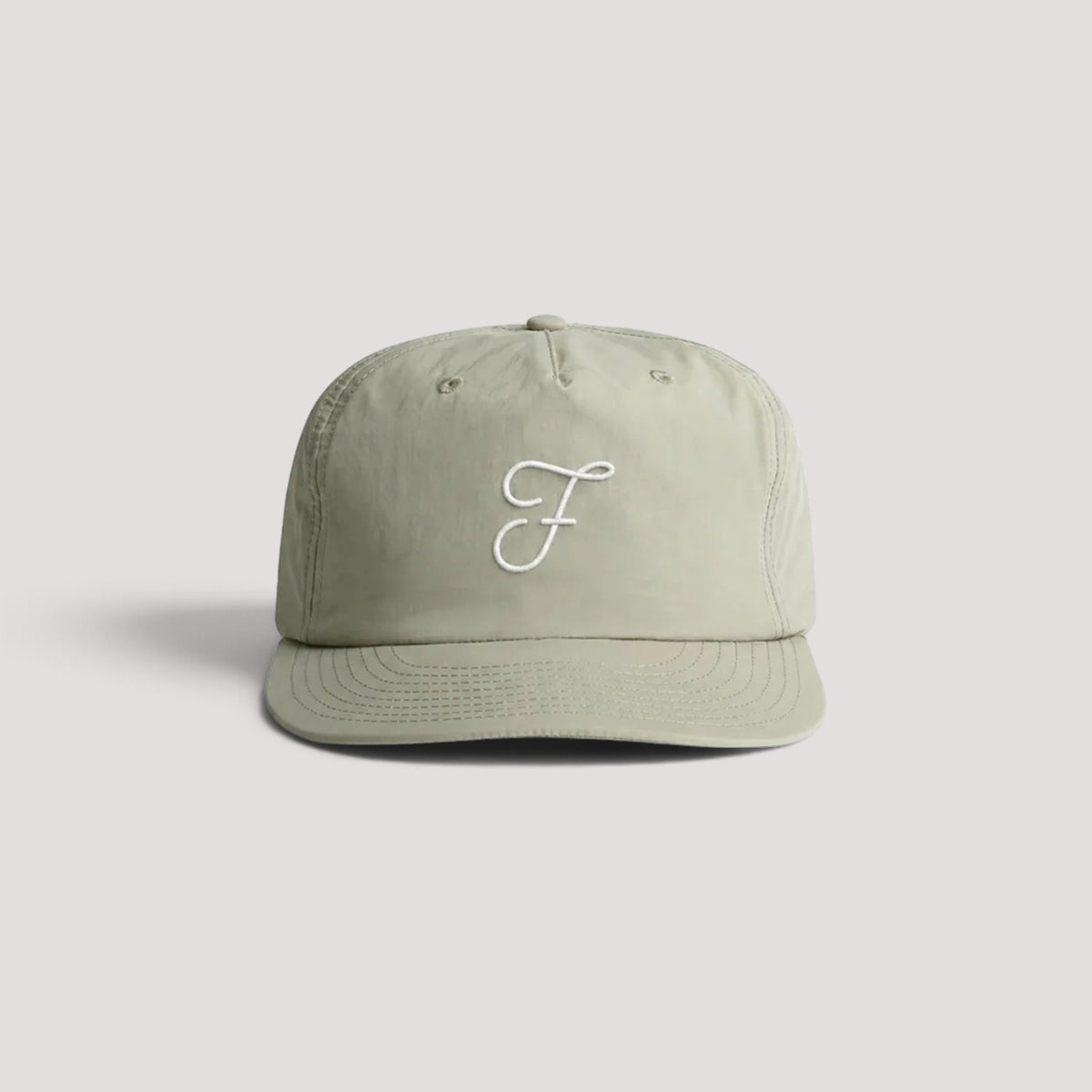 A light sage green hat with a white embroidered cursive 'F' logo on the front, set against a solid light gray background.